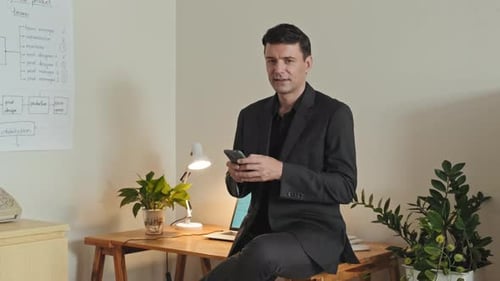 Portrait of Attractive Businessman with Smartphone in Office