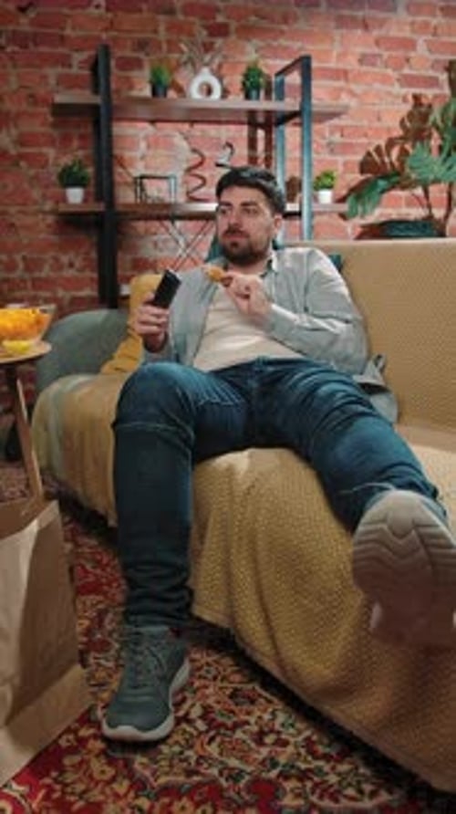 Bearded Man Spending Time at Home with Fast Food Delivery Lays on Couch Watching Tv Switching