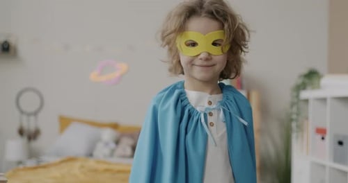 Slow Motion Portrait of Adorable Kid Moving Super Hero Cape Away From His Face Looking at Camera