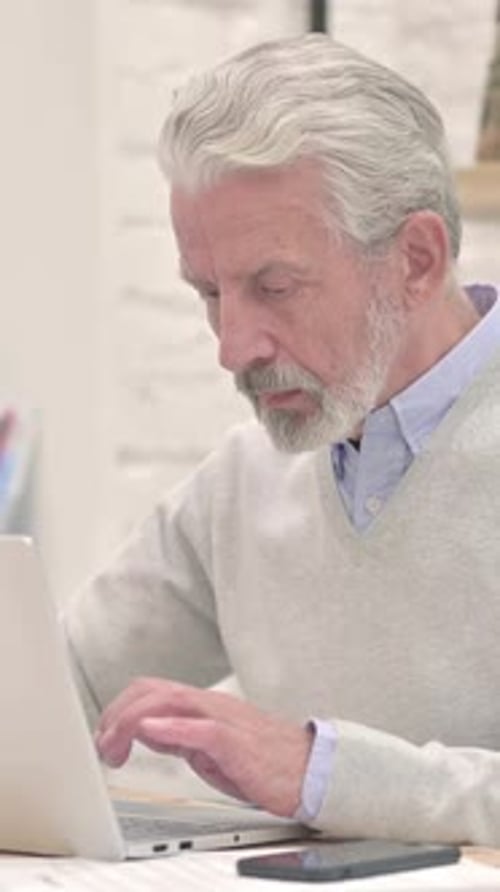 Senior Man Working on Laptop Computer Indoors