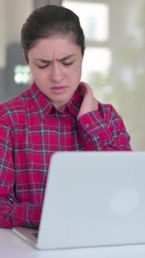 Woman Using Laptop Massages Sore Neck Indoors