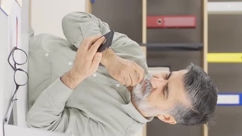 Thoughtful Man Types on Smartphone in Office