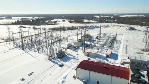 Anordnung des Hochspannungs-Umspannwerks und des Übertragungsnetzes in einer schneebedeckten Winterlandschaft