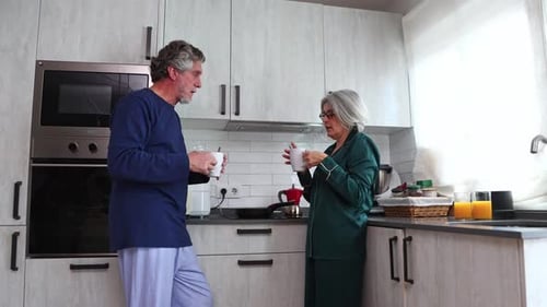 Couple in pajamas drinking coffee in kitchen