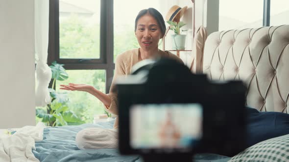 Feliz chica asiática influencer con pijama blanco crema grabando ...