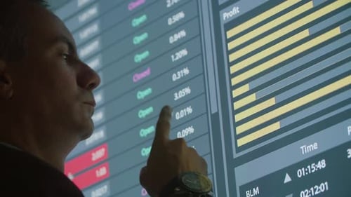 Pensive Man Looking at Bar Charts on Big Digital Screen
