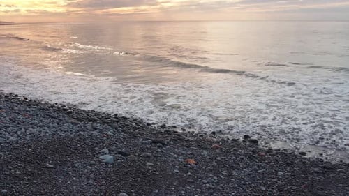 Zeitlupe von Wellen, die während des Sonnenaufgangs in der Goldenen Stunde an der Küste von Pebble Beach zusammenbrechen
