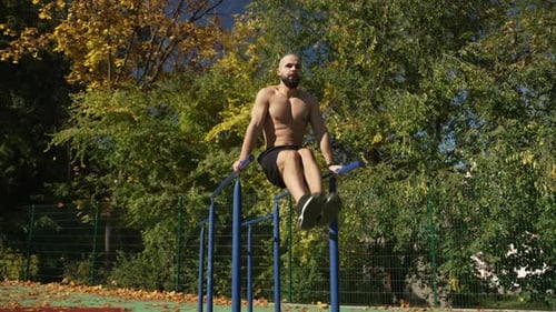 The Athlete Swings the Press on the Horizontal Bar Raising His Legs to the Top