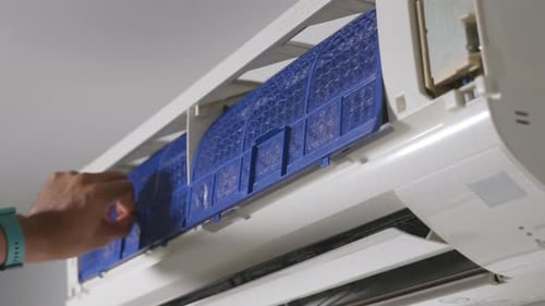 Technician placing back clean filter into air conditioner