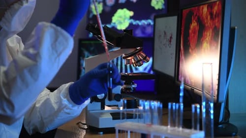 A man in biological defense works in a viral laboratory. He looks at the samples under an microscope