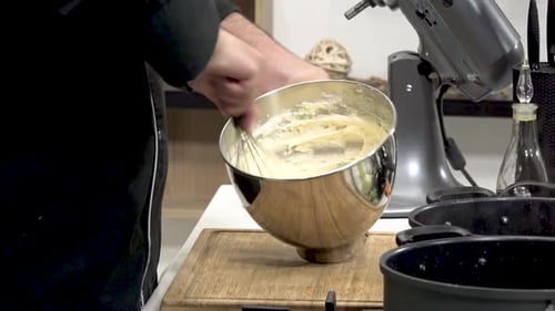 Chef mixes cake batter in a stainless steel bowl in a modern kitchen during an evening baking sessio