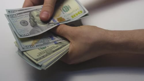 Banknotes of Cash Dollars of Money are Held in the Hands of a White Man Put in a Stack a Bundle