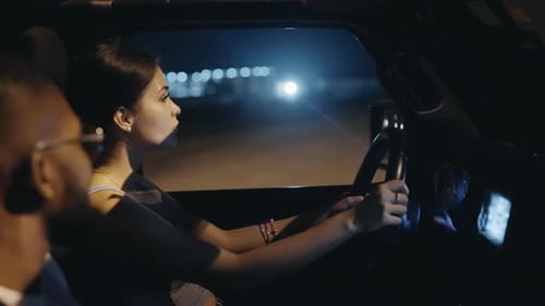 Woman Driver With Passenger Looks At The Opposite Road While Driving At Night