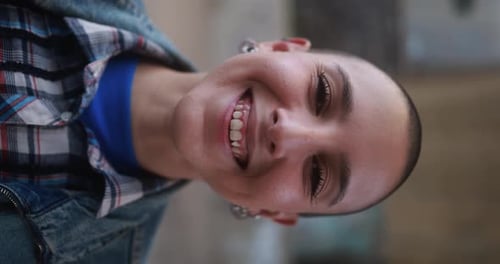 Junge glatzköpfige Frau lächelt im Freien vor der Kamera - Vertikales Video
