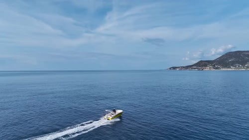 Aerial Video of a Motorboat Leaving a Foamy Trail As It Heads Towards the Harbor on a Bright Blue