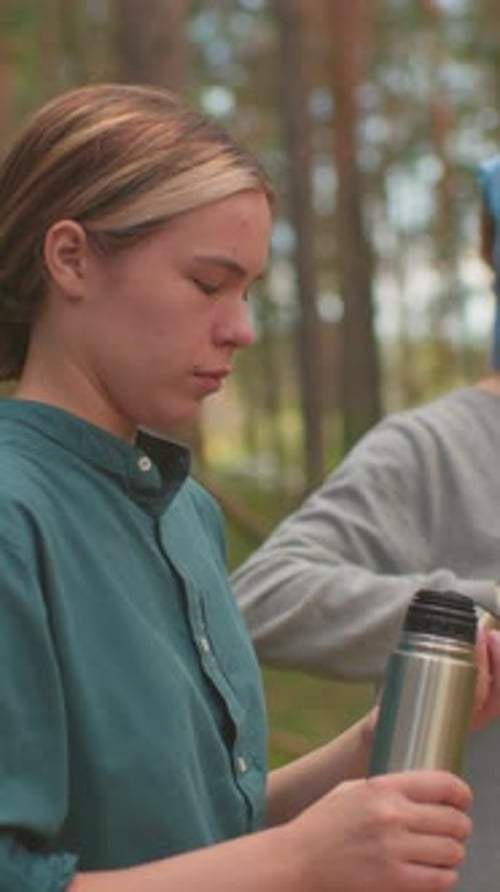 Sisters Enjoy Peaceful Break in Forest with Thermos and Hair Care