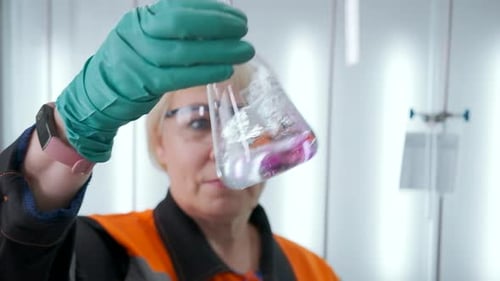 Woman Mixing Pink Liquid in Flask in Lab