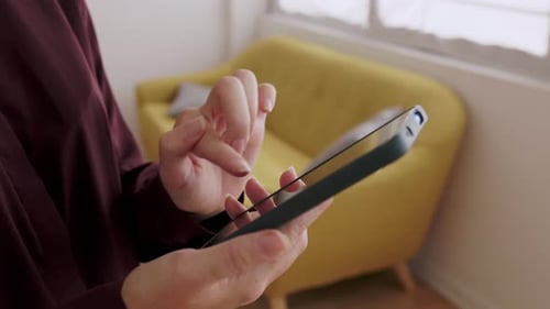 Close Up of Unrecognizable Woman Using Mobile Phone Touchscreen at Home