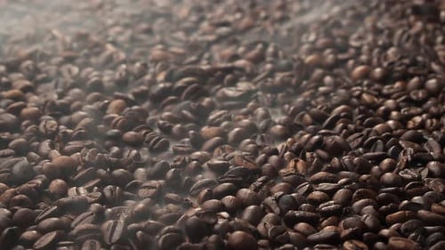 Roasted coffee beans. The smoke comes from fresh coffee seeds.