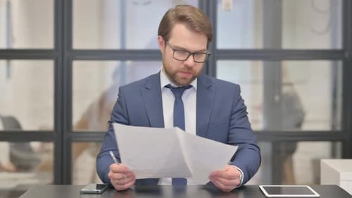 Adult Reviews and Edits Documents at Office Desk