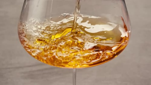 Orange or White Wine Bottle and Glass Against a Sunset in a Peaceful Vineyard Pouring of Ecological