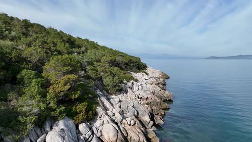 Flying close to the rocky coast next to the calm sea