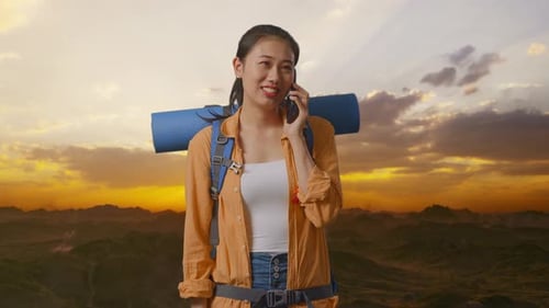 Asian Female Hiker Smiling And Talking On Smartphone On The Top Of Mountain