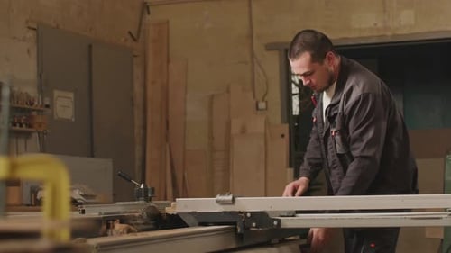 Man Cutting Wood with Table Saw in Workshop