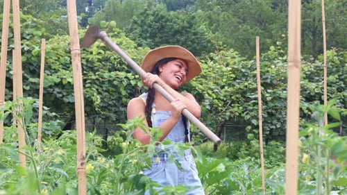 Latin farmer woman swinging a hoe in a vegetable garden