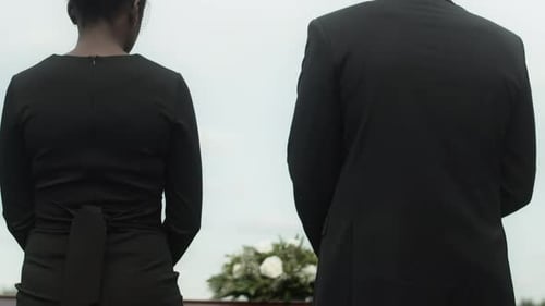 Couple Holding Hands at Funeral by Casket
