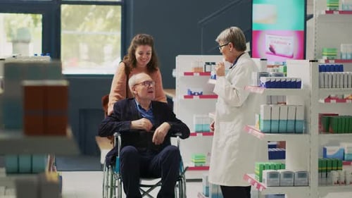 Pharmacist Consults Senior Man in Wheelchair at Pharmacy