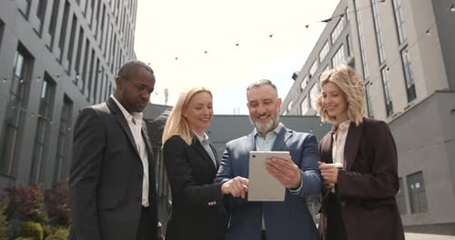 Team of Colleagues Using Tablet Outside Modern Offices