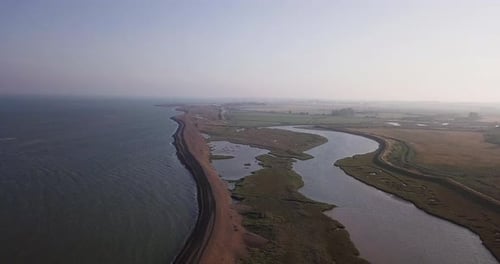 Aerial shot tracking backwards showing Shingle Street beach in rural United Kingdom. Narrow strip of