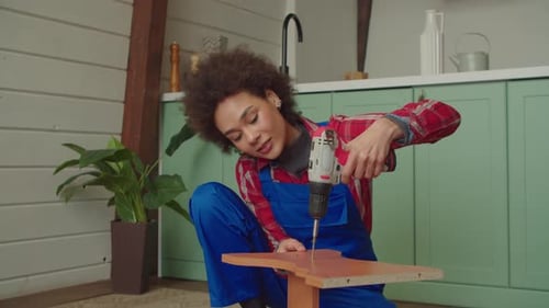 Black Female Repairing Furniture and Unscrewing Screws with Cordless Screwdriver