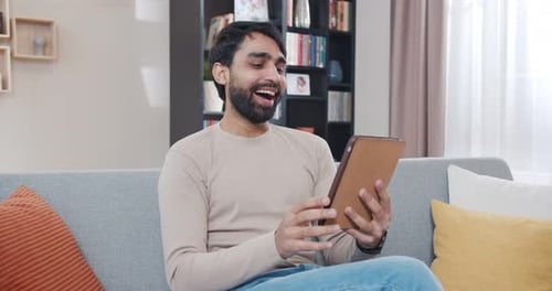 Young Man Using Tablet on Couch at Home