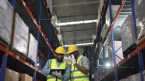 Blue collar workers are working at warehouse.