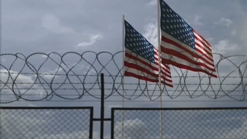American Flags Waving Behind Barbed Wire Fence