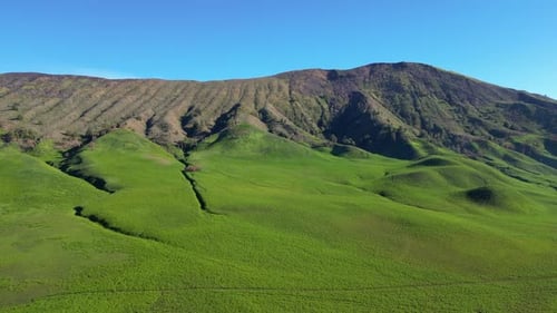 Scenic Aerial View of Green Hills and Mountains Under Blue Sky in Bromo Mountain