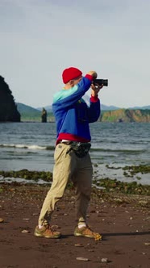 Man Prepares Camera on Rocky Coastal Beach