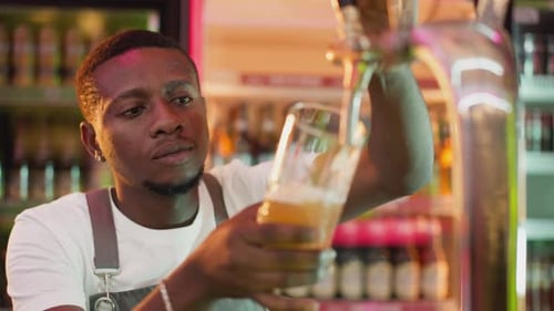 Barman Pours Ale Into Glass in Bar Closeup