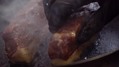 Grilling seasoned meat steak in hot pan. Chef hands flip the stake. Close up shot. Cooking Brazilian