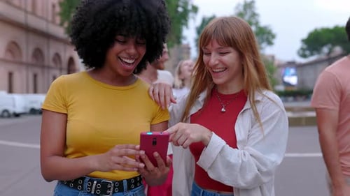 Two Friends Laughing at Mobile Phone in City