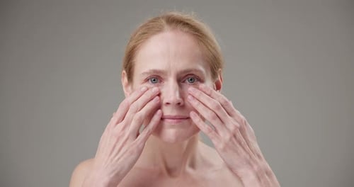 Woman Massaging Face and Neck in Studio