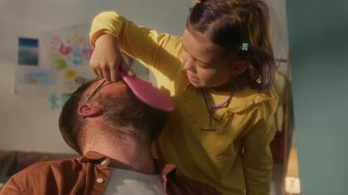 Child Combing Man's Hair Affectionately Indoors During the Day