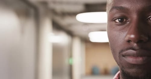 Close-up of African American man in office hallway, focusing on professional expression, copy space