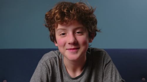 Boy Talking Indoors on Camera with Blue Background