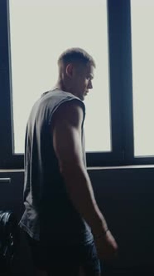 Athletic Man Standing in Gym With Weightlifting Equipment in Background