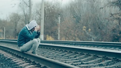 Desperate Man Sitting on Railroad
