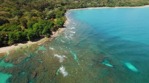 Aerial view of turquoise sea and coral reef on jungle beach in tropics in Costa Rica
