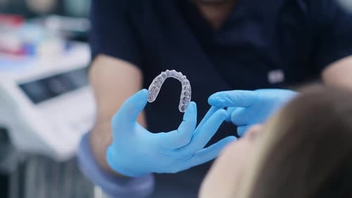Orthodontiste portant des gants en caoutchouc tenant des gouttières transparentes pour corriger la dentition